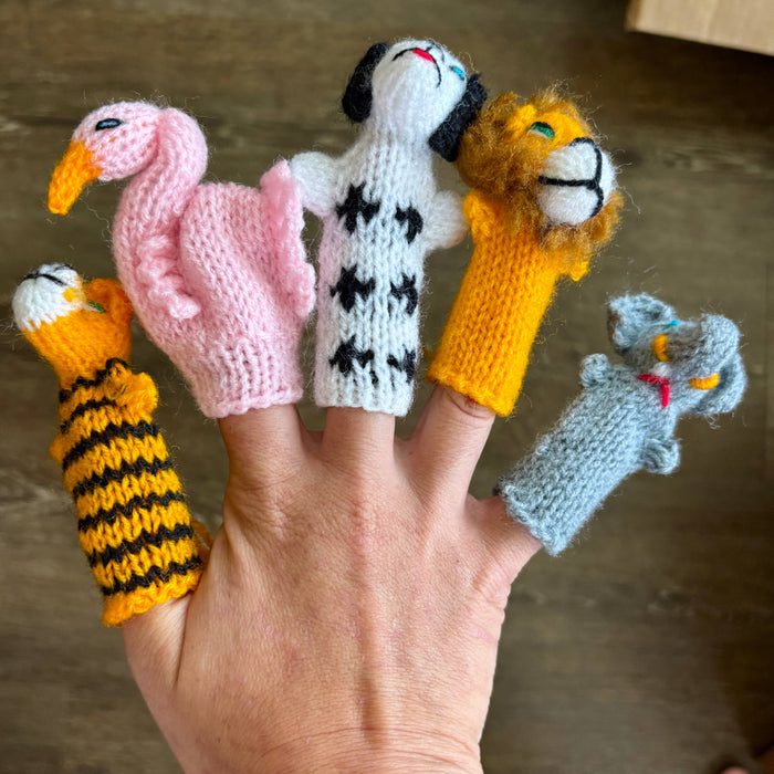 Hand with knitted finger puppets of various animals on a neutral background